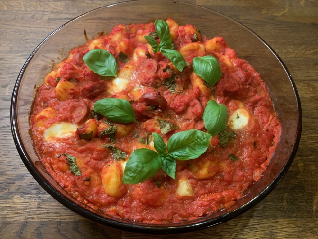 En gratäng med gnocchi, chorizo och mozzarella i tomatsås i en ugnsfast glasform.