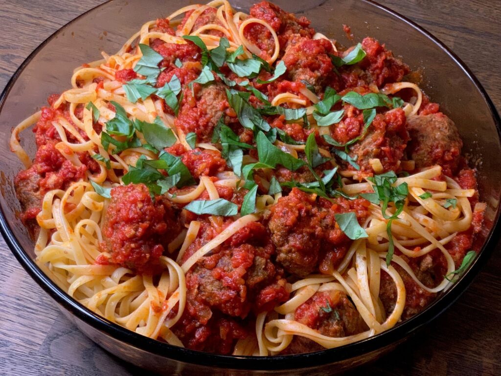 Köttbullar i tomatsås med linguine toppad med färsk finklippt basilika.