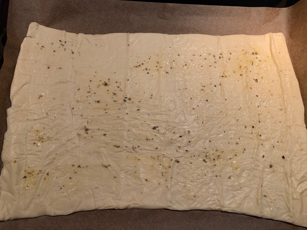 Rektangulär pizzadeg med smält smör och pizzakrydda